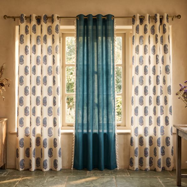 Blue sheer curtains layered with white printed curtains on a curtain rod in front of a large window